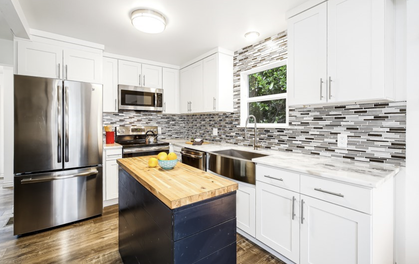 Bright updated farmhouse kitchen with modern tile backsplash and butcher block island